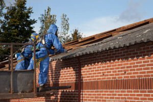 Two men in protective gear safely removing asbestos while working on a roof.